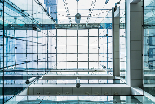 Upward view through a glass-and-steel atrium, daylight filtering through the glazed roof