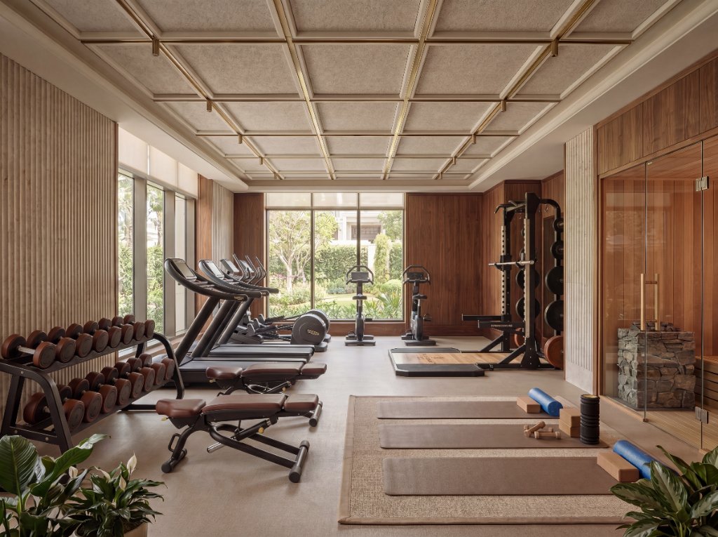 Warm luxury hotel fitness suite with wood panelling and garden views