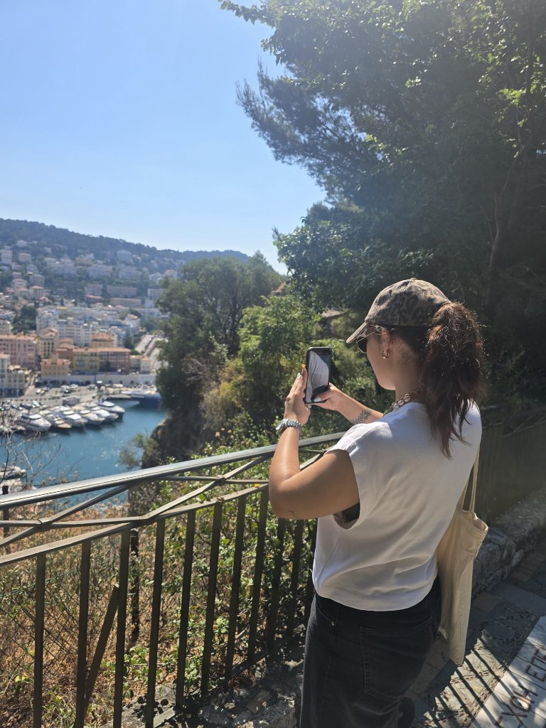 Visiteur photographiant la baie de Nice et le port avec son smartphone depuis un point de vue