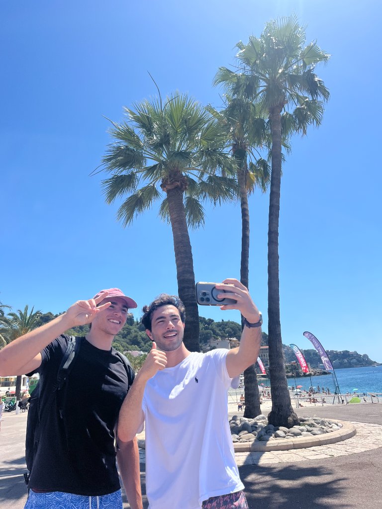 Deux amis prenant un selfie devant les palmiers et la Méditerranée à Nice
