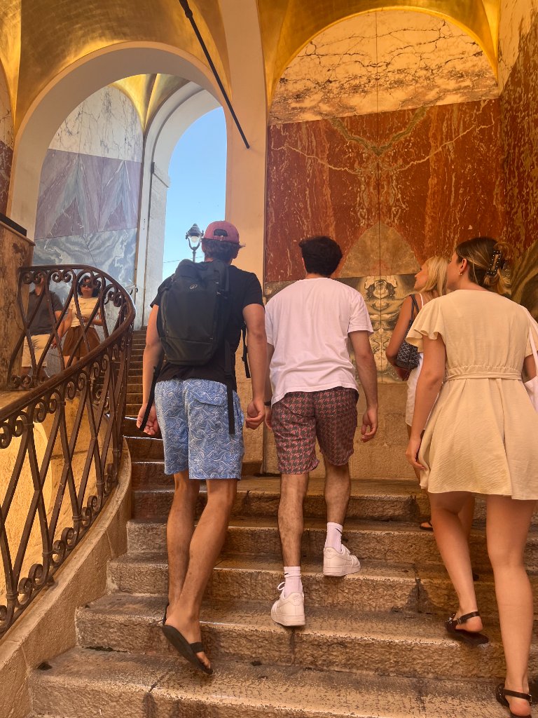 Groupe d'amis montant un escalier en pierre dans un passage voûté de Nice