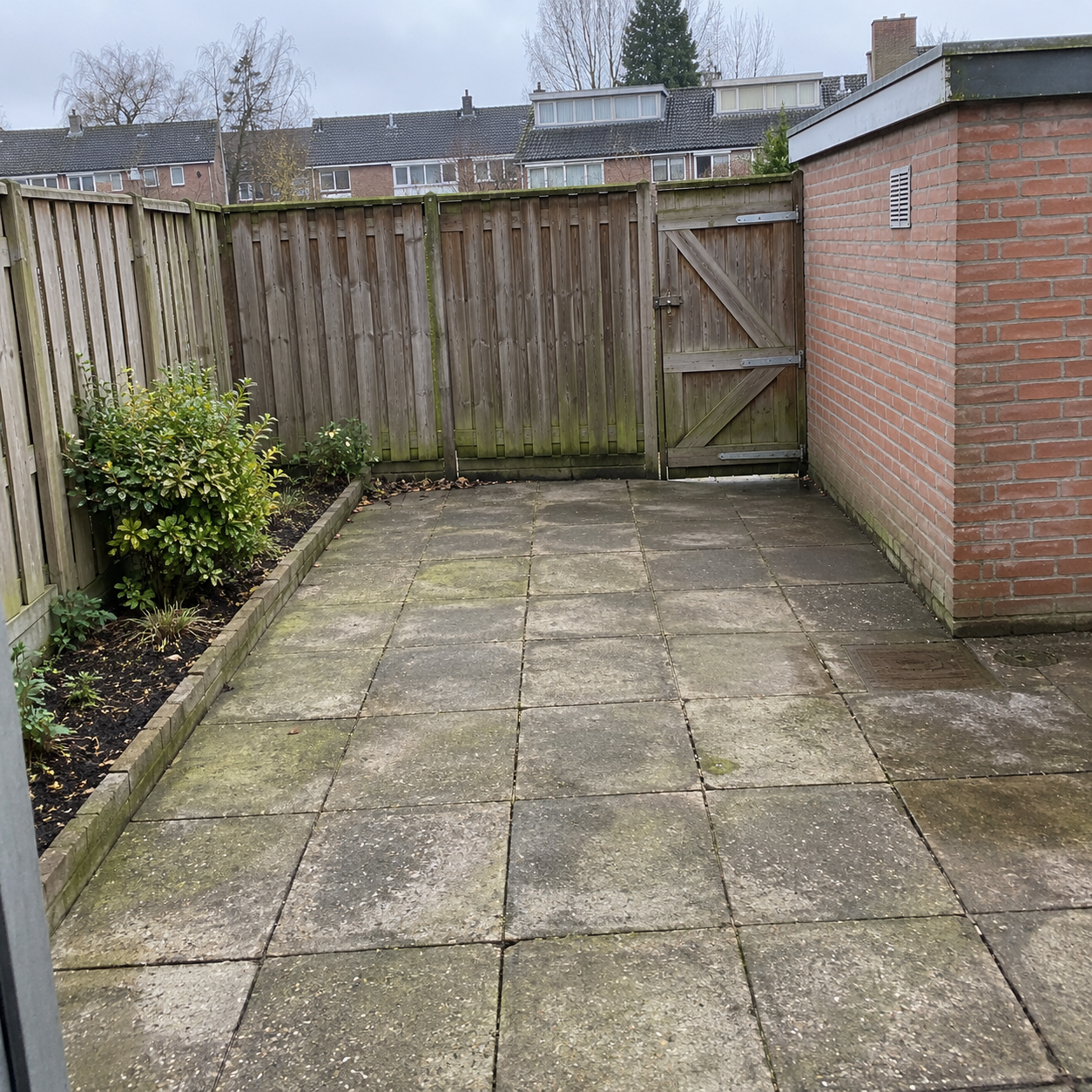 Netjes leeggehaalde en aangeveegde achtertuin met schuur