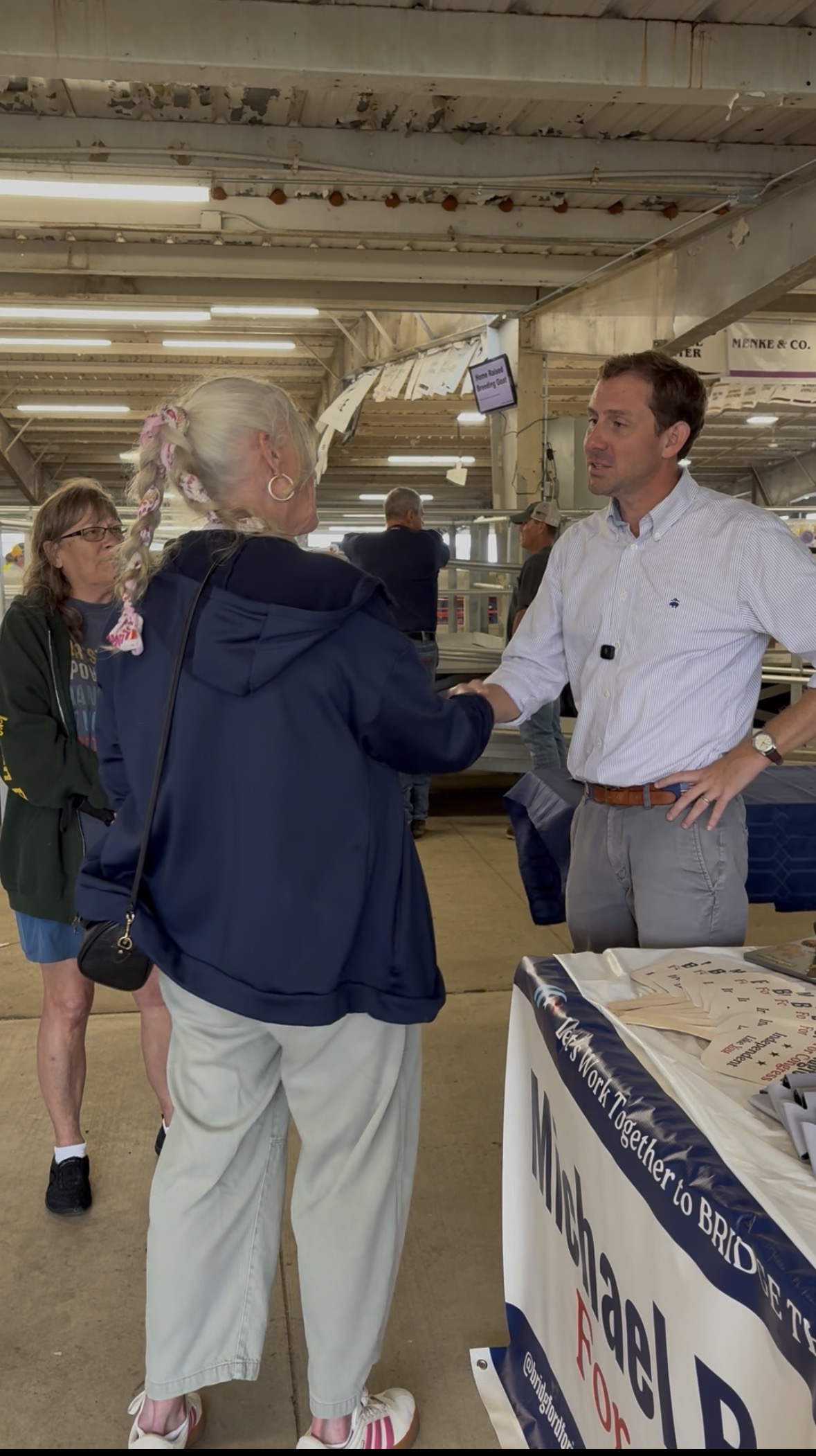Michael Bridgford shaking hands with a supporter at a campaign table