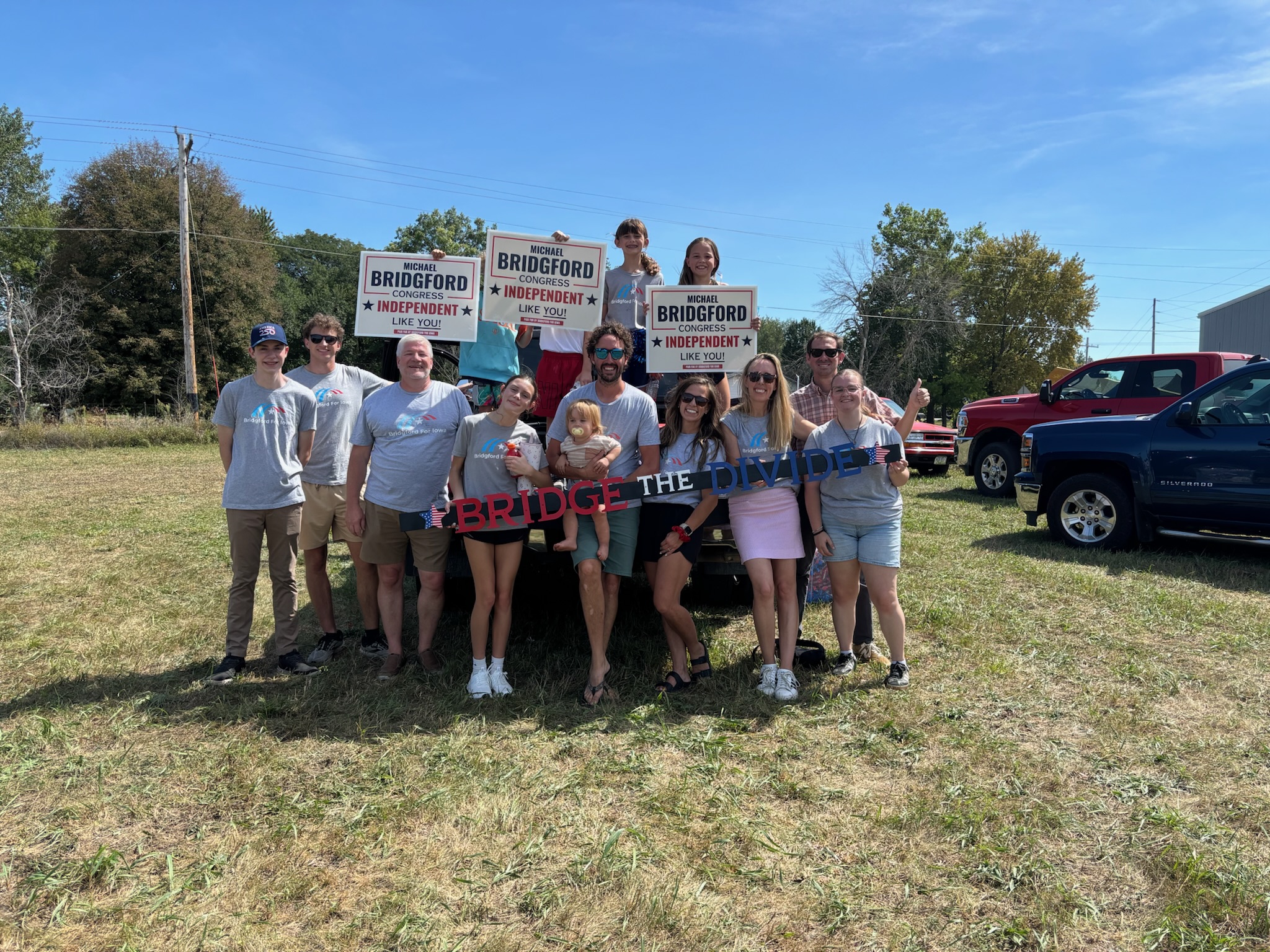 Group of supporters holding campaign signs behind a truck