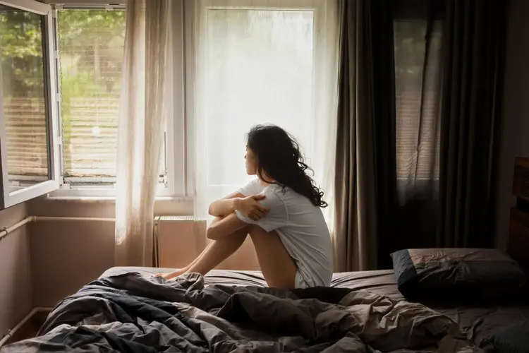 Person sitting on bed looking out window, Vastu home energy
