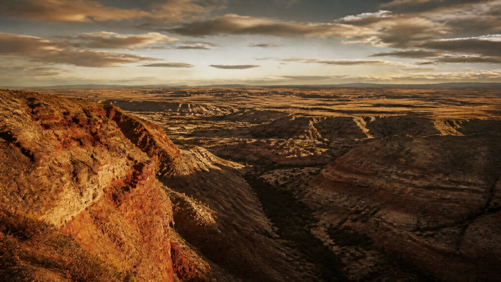 Dramatic badlands landscape showing erosion patterns and vast Montana plains under dramatic sky