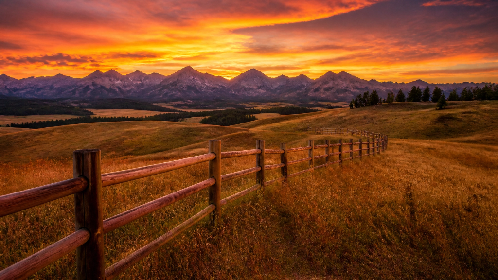 Montana ranch fence at golden sunset with mountain peaks