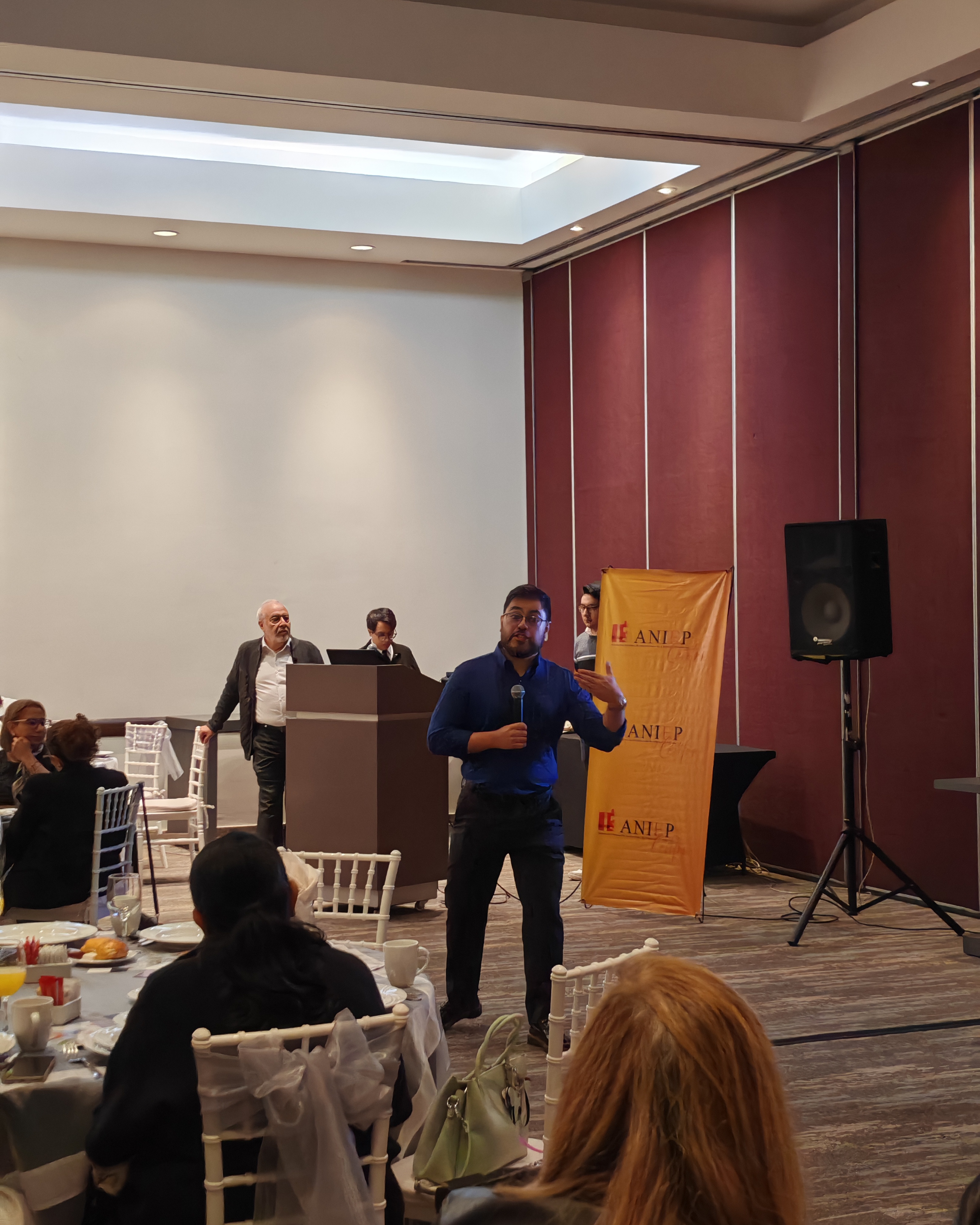 Ponente presentando frente a asistentes en un desayuno temático