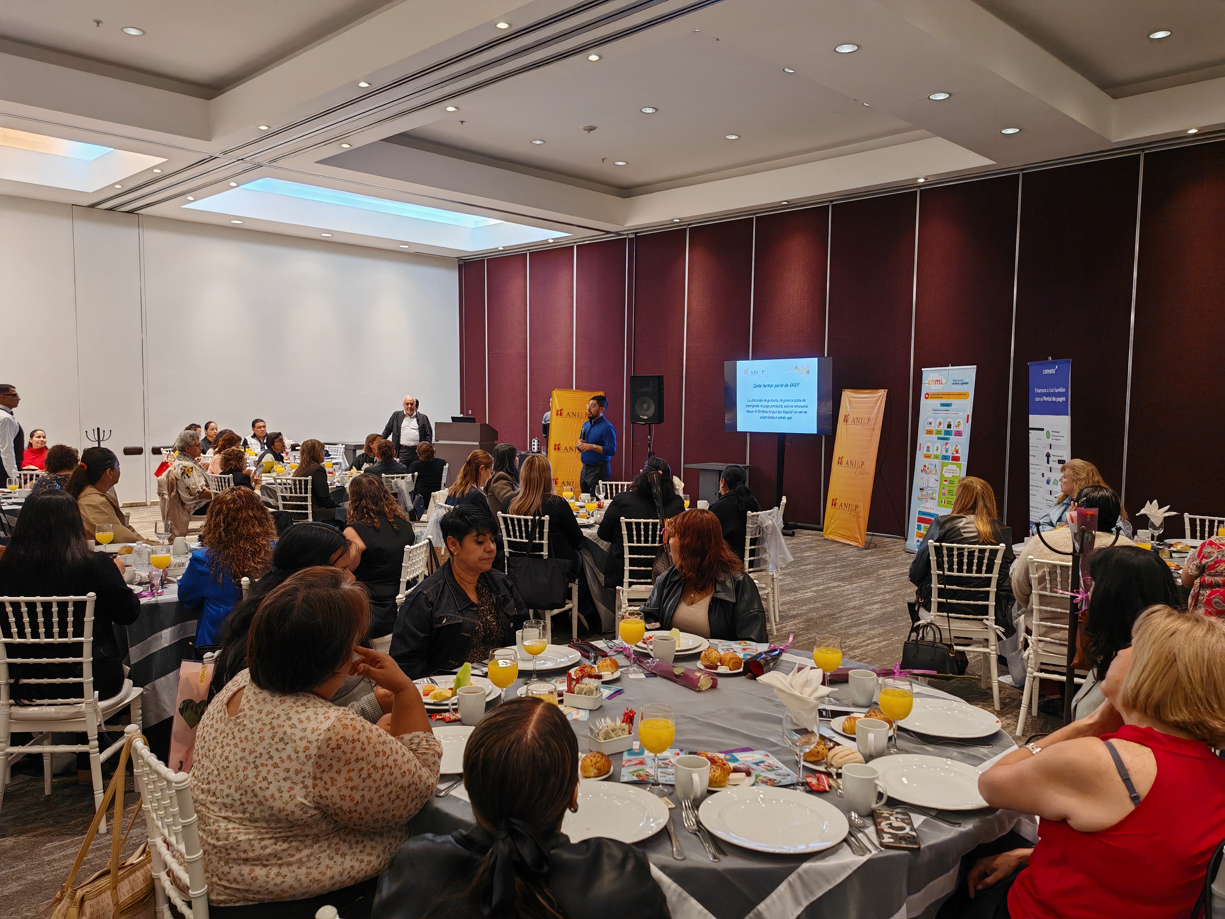 Auditorio de un desayuno ejecutivo con ponente y marquesinas de proveedores
