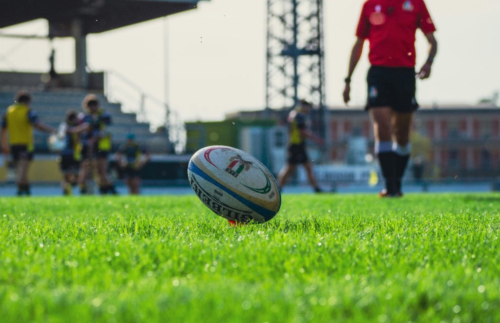 A Gilbert rugby ball on a kicking tee on a green pitch