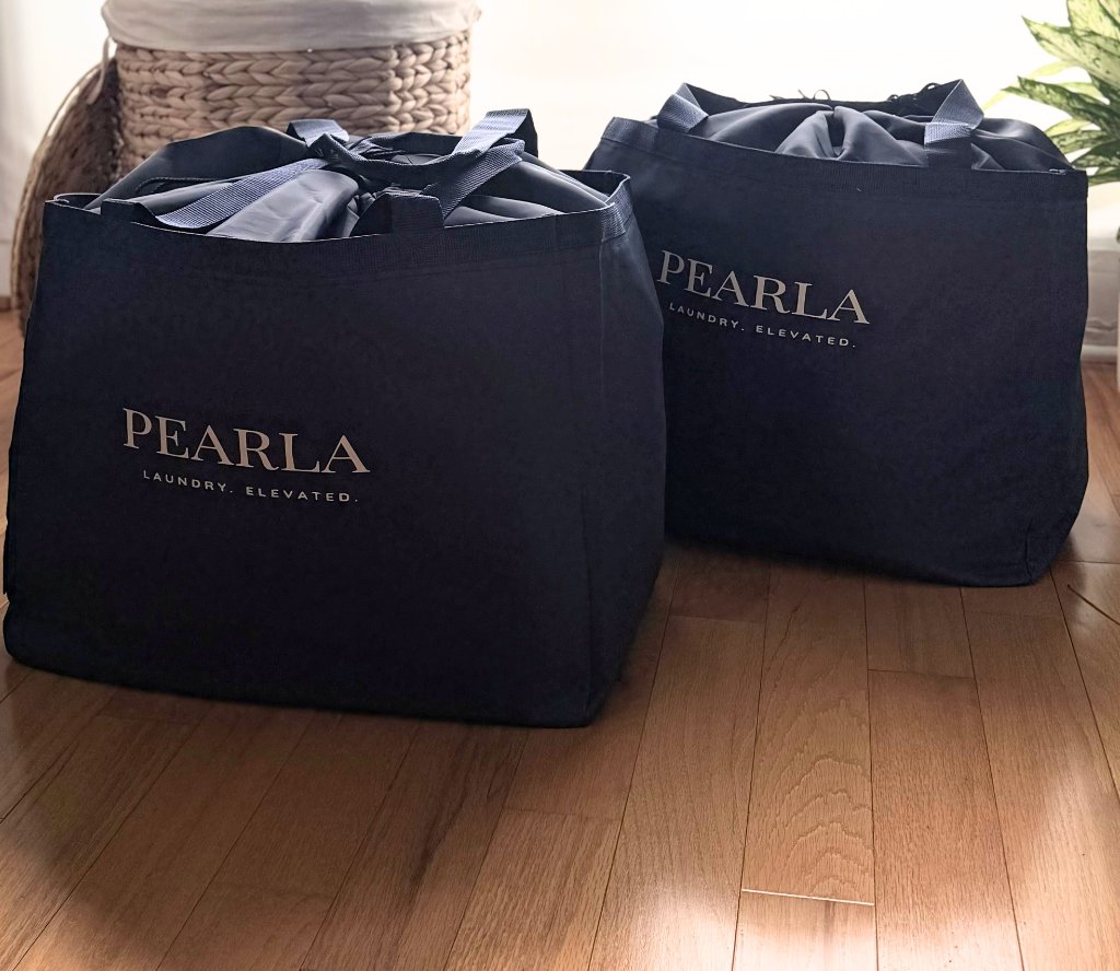 Two Pearla bags with drawstring liners on a hardwood floor