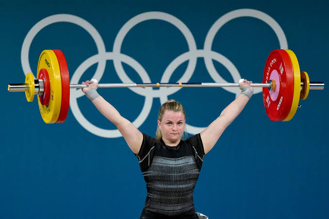Olympic-style weightlifter pressing a loaded barbell overhead