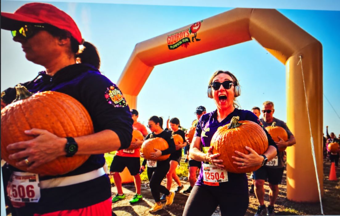 Runners carrying pumpkins through the Halloween Pumpkin Race