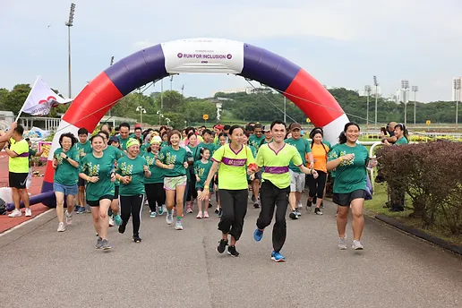 Run for Inclusion participants running through the event start arch