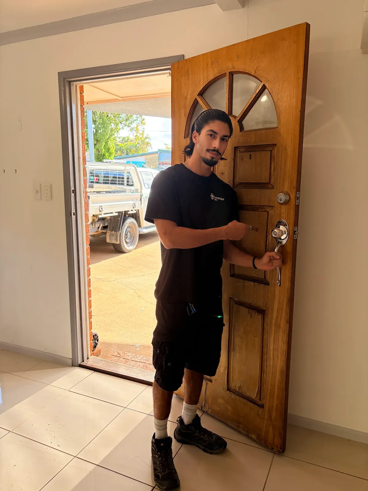 LockOps technician with a timber front door fitted with a new deadbolt and handle set