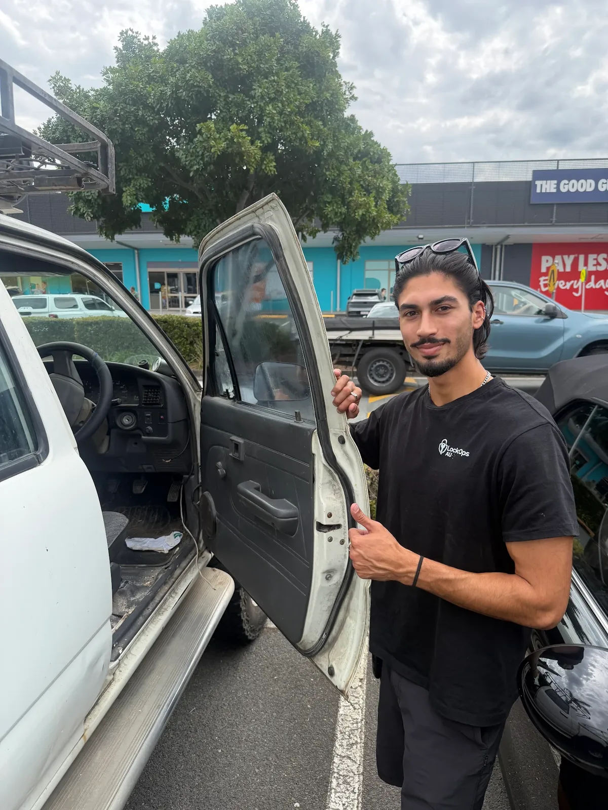 LockOps technician giving a thumbs up beside an opened ute door in a shopping centre car park