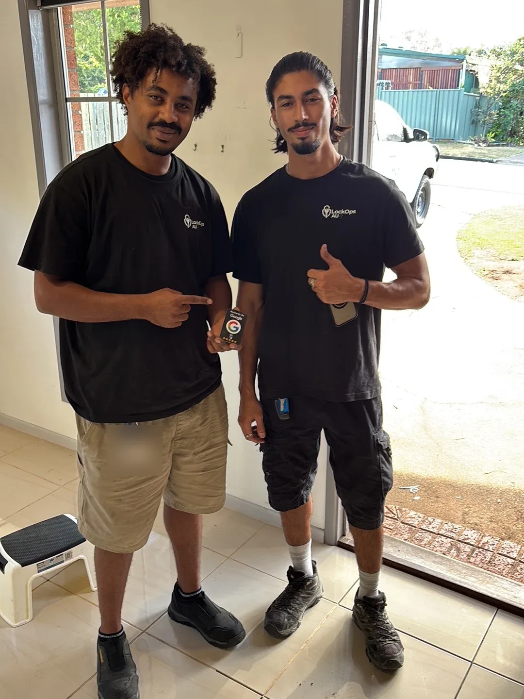 The two LockOps AU technicians in uniform holding a Google review card