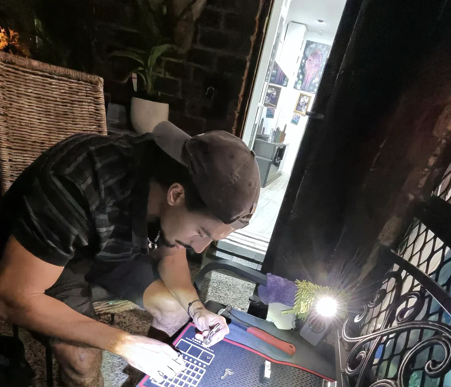 LockOps technician rekeying a lock cylinder on a pinning mat at the customer's door at night