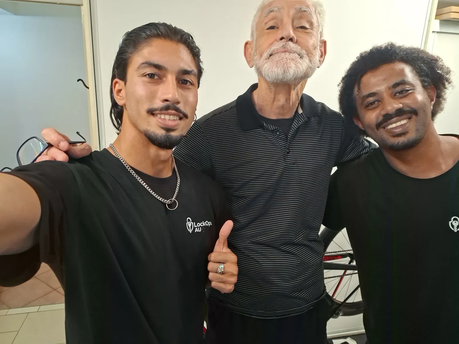 Both LockOps technicians with a smiling older customer giving a thumbs up