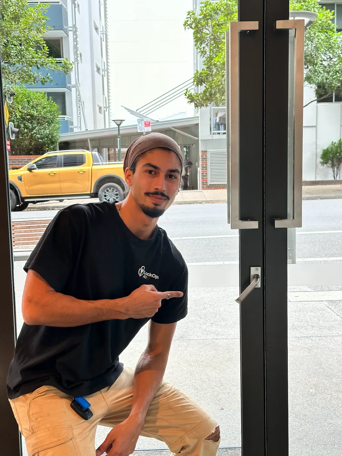 LockOps technician at a shopfront glass door with pull handles and a lock