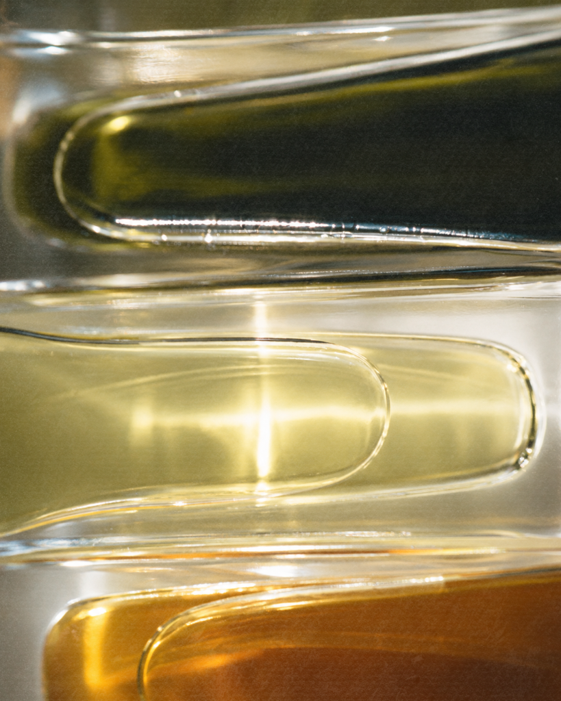 Stacked glass lab vessels with green, golden, and amber liquids