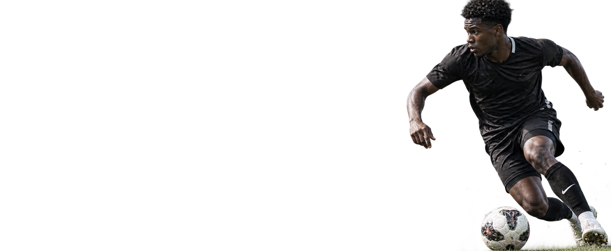 Soccer player dribbling a ball against a black field