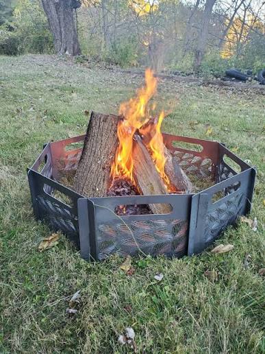 Campfire ring — small campfire in a hexagonal metal fire pit at golden hour