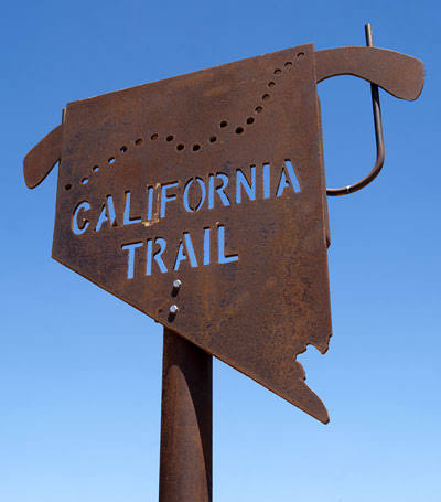 Weathered California Trail trailhead sign — rusted metal cutout against blue sky