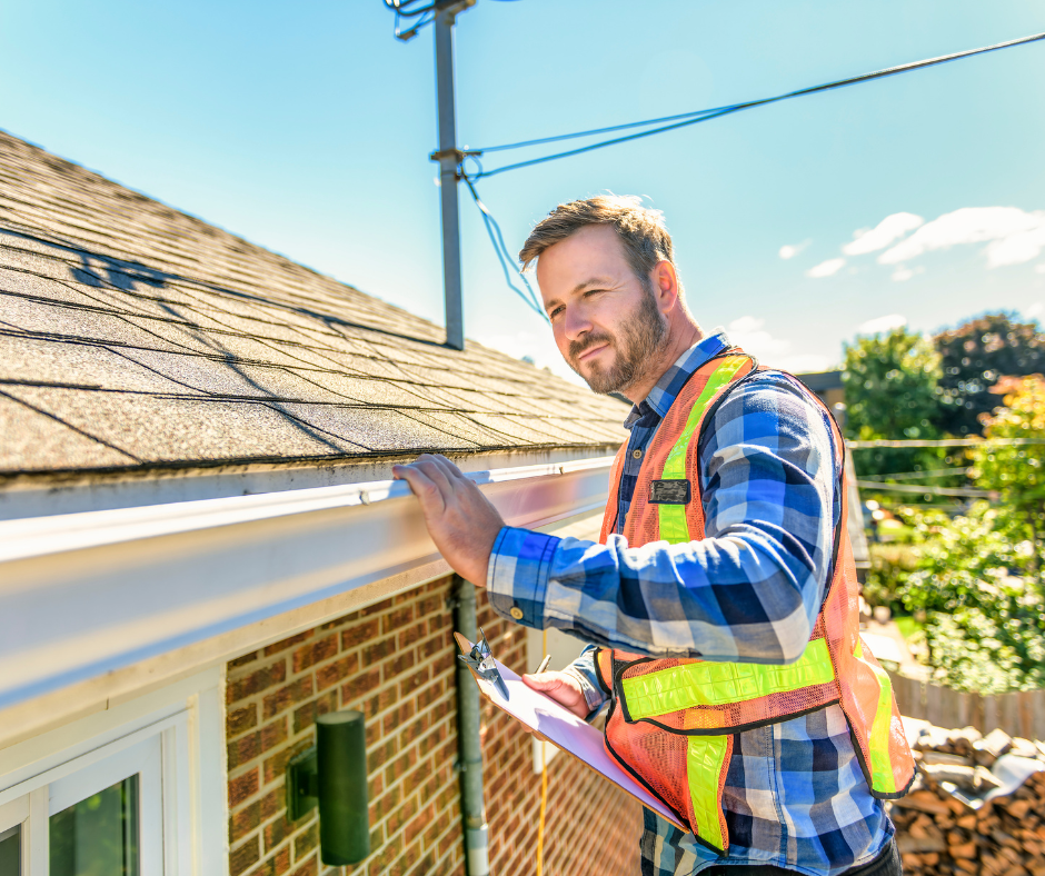 Roofing inspector in safety vest evaluating a residential roof and gutter system