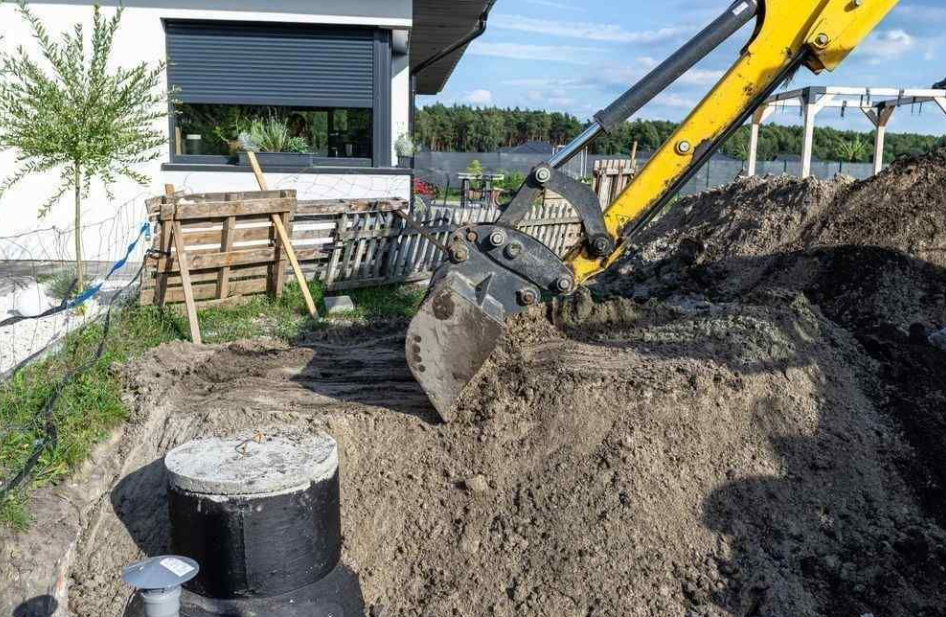 Yellow excavator excavating for septic tank installation