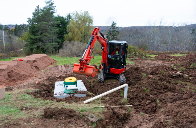 Red excavator working on septic system installation