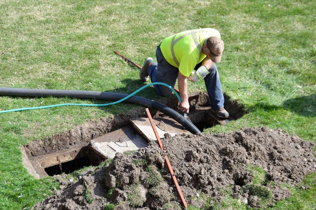 Contractor inspecting septic tank system in yard