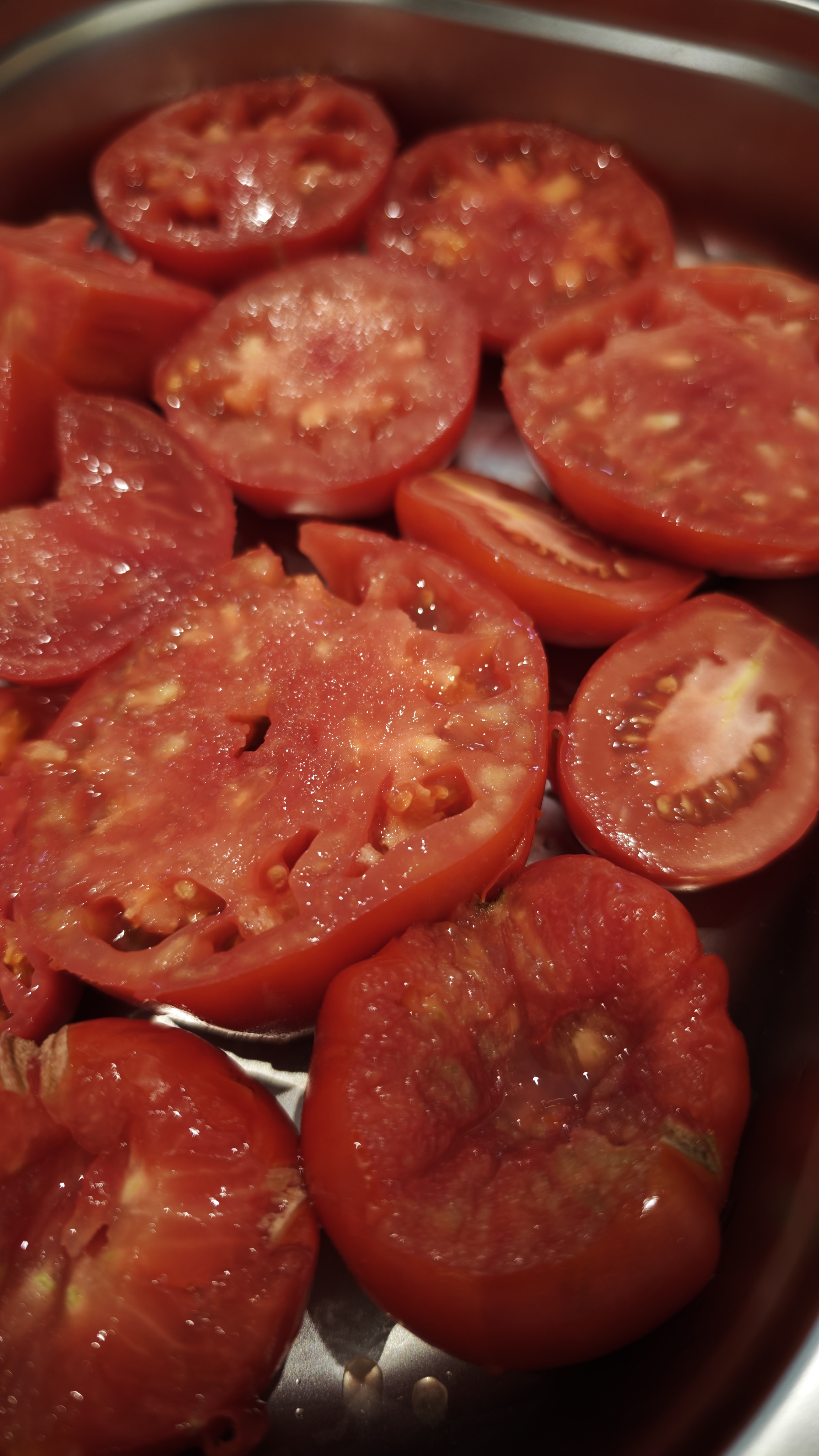 Halbierte Tomaten mit sichtbaren Kernen in einer Metallschale