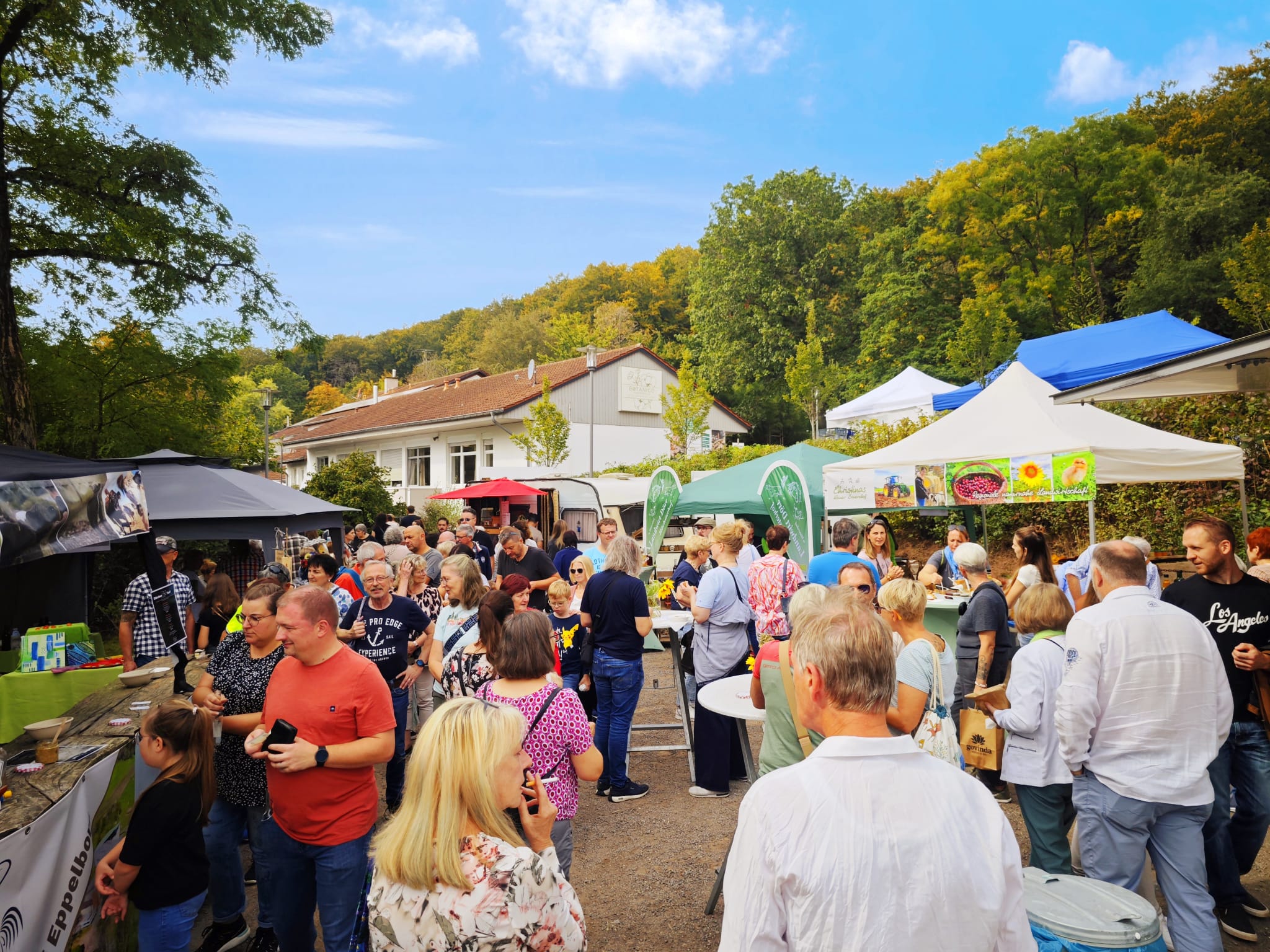 Besucher auf dem Herbstmarkt Finkenrech zwischen Verkaufsständen und Bäumen