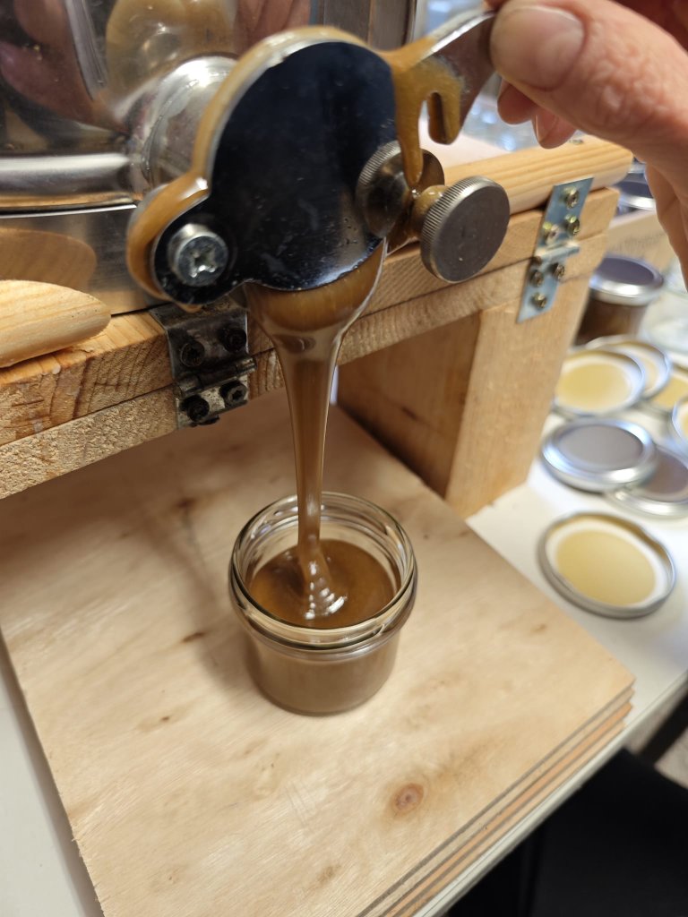 Honig wird aus einem Edelstahlhahn in ein Glas abgefüllt
