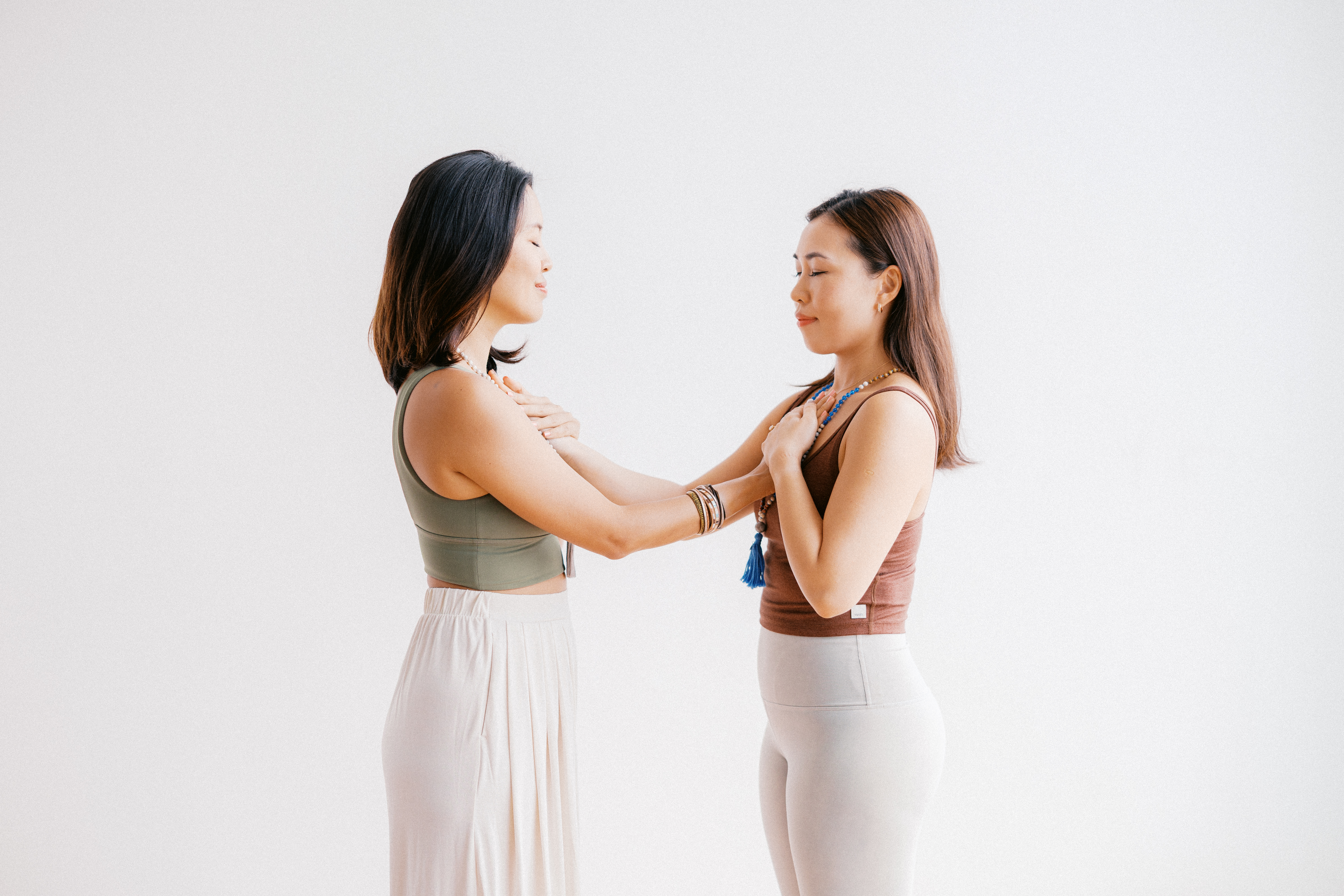 Two women standing face-to-face in a calm, meditative grounding pose during the OASIS Outreach Wellbeing Series