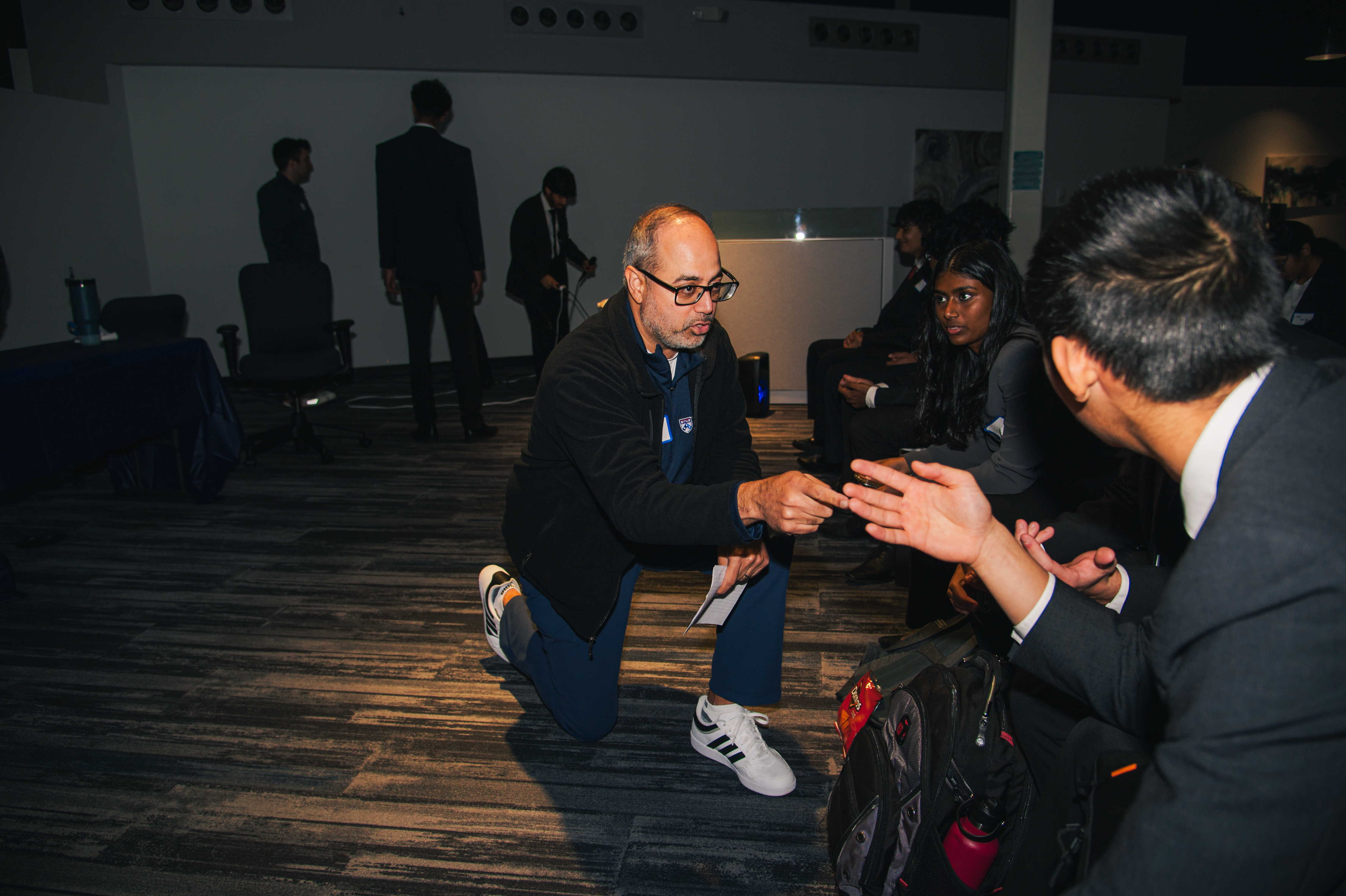 A judge crouched beside a seated participant, talking through her idea at a Project Finnovate competition
