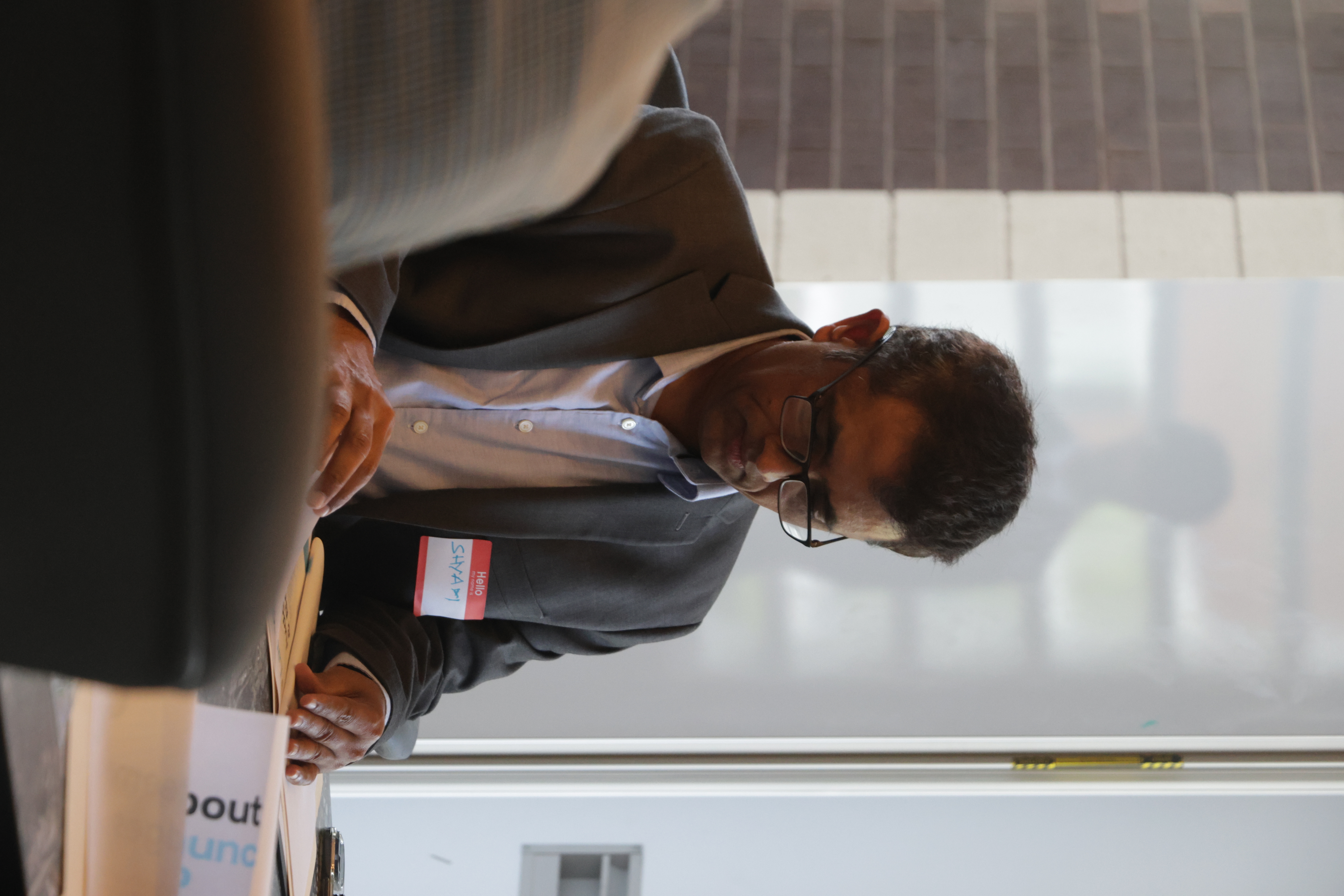 A participant seated at a conference table wearing a name tag during Launch Up