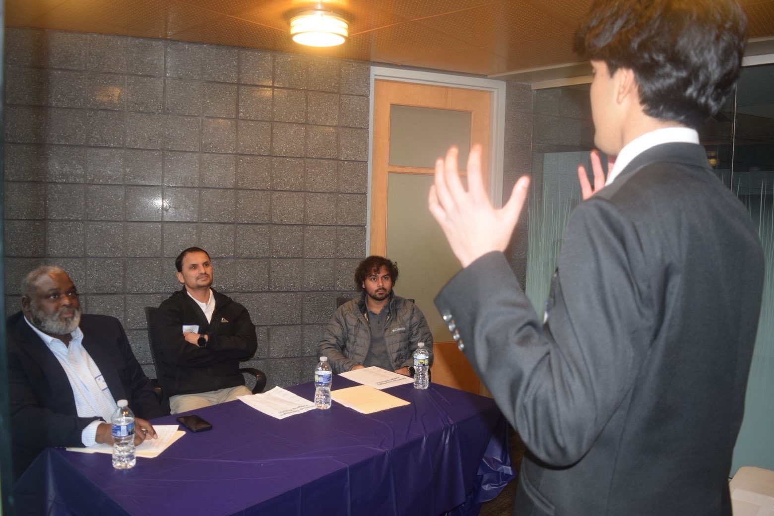 A presenter gesturing while pitching to a panel of judges at Startup Spotlight
