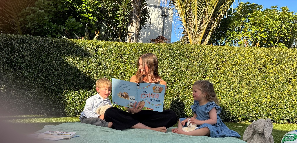 Reading a book to children on the grass