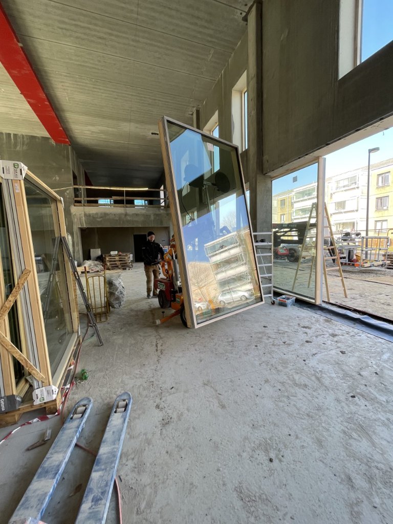 JB Entreprise smed transporterer stor glasrude indendørs med el-truck – vinduesmontering på byggeplads