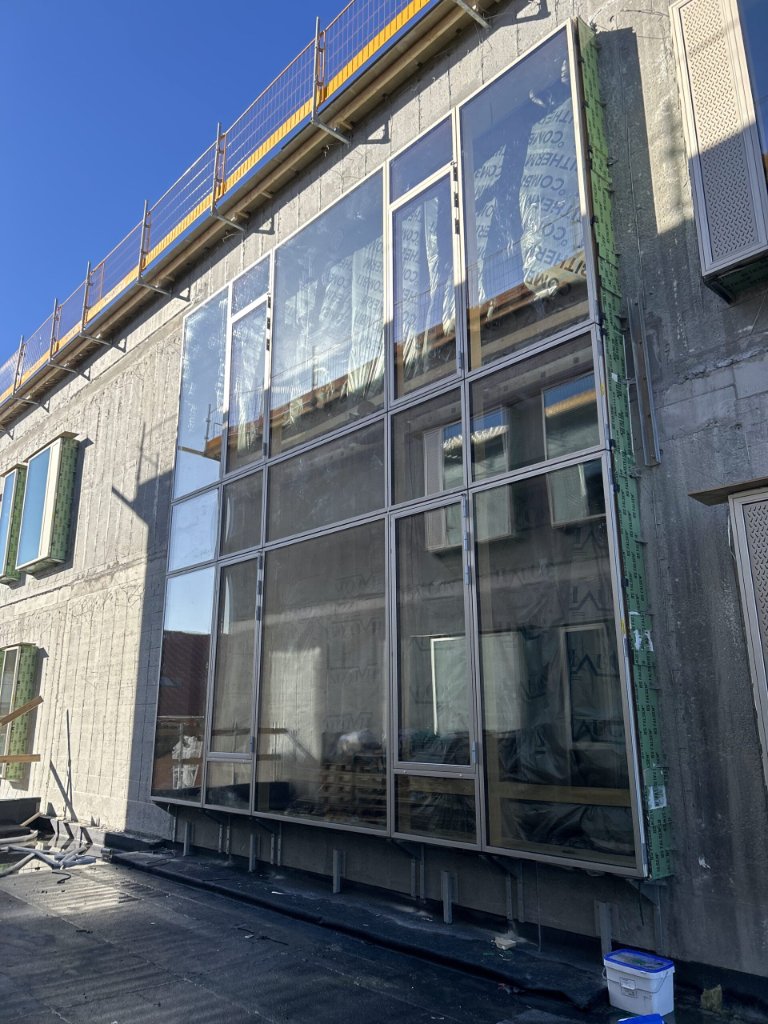 Stort aluminiumsglasfacadesystem under montering på betonbygning – JB Entreprise vinduesudskiftning