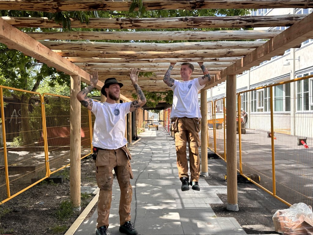 To JB Entreprise svende fejrer færdig pergola ved skole – trækonstruktion i naturtræ