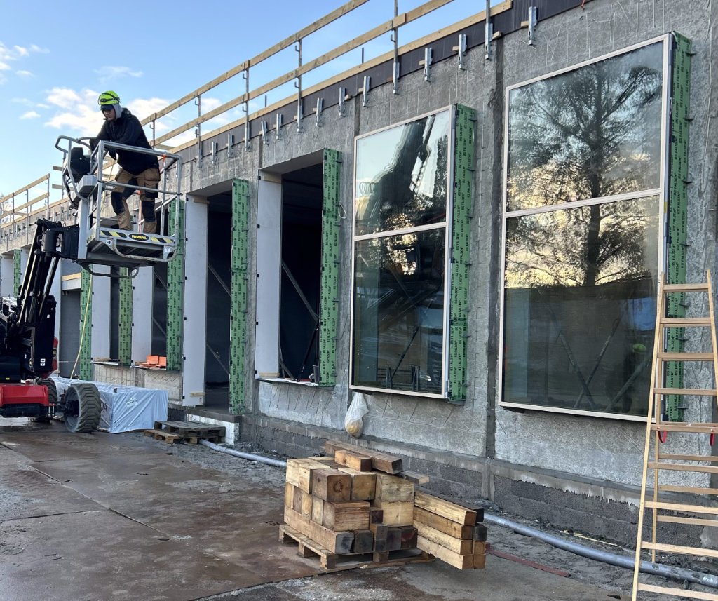 JB Entreprise smed på lift monterer store vinduer i betonvæg på byggeplads – vinduesudskiftning
