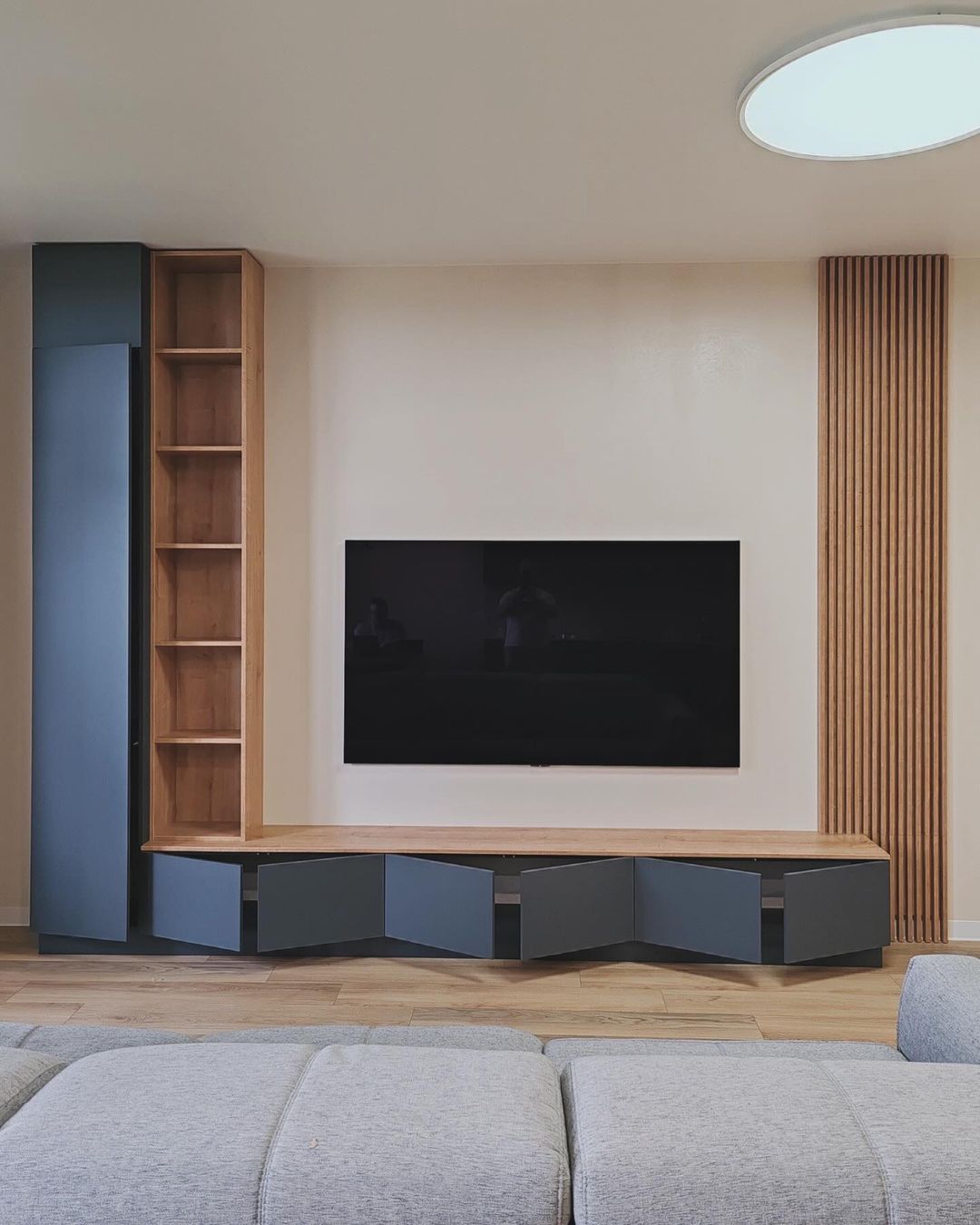 Sala com marcenaria em azul escuro, nichos amadeirados e painel ripado lateral — Ornale Planejados