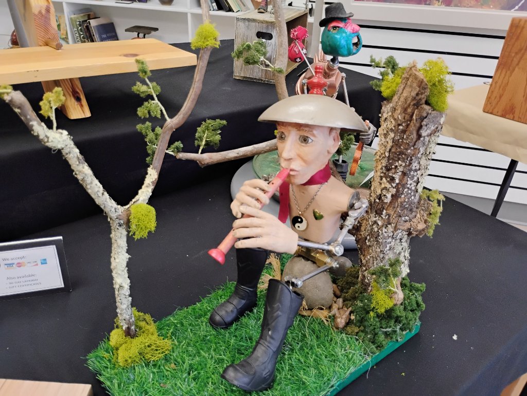 Mixed media sculpture of a musician in a forest scene