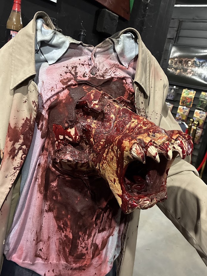 Gruesome horror prop featuring a creature bursting from a mannequin's chest in a blood-stained shirt