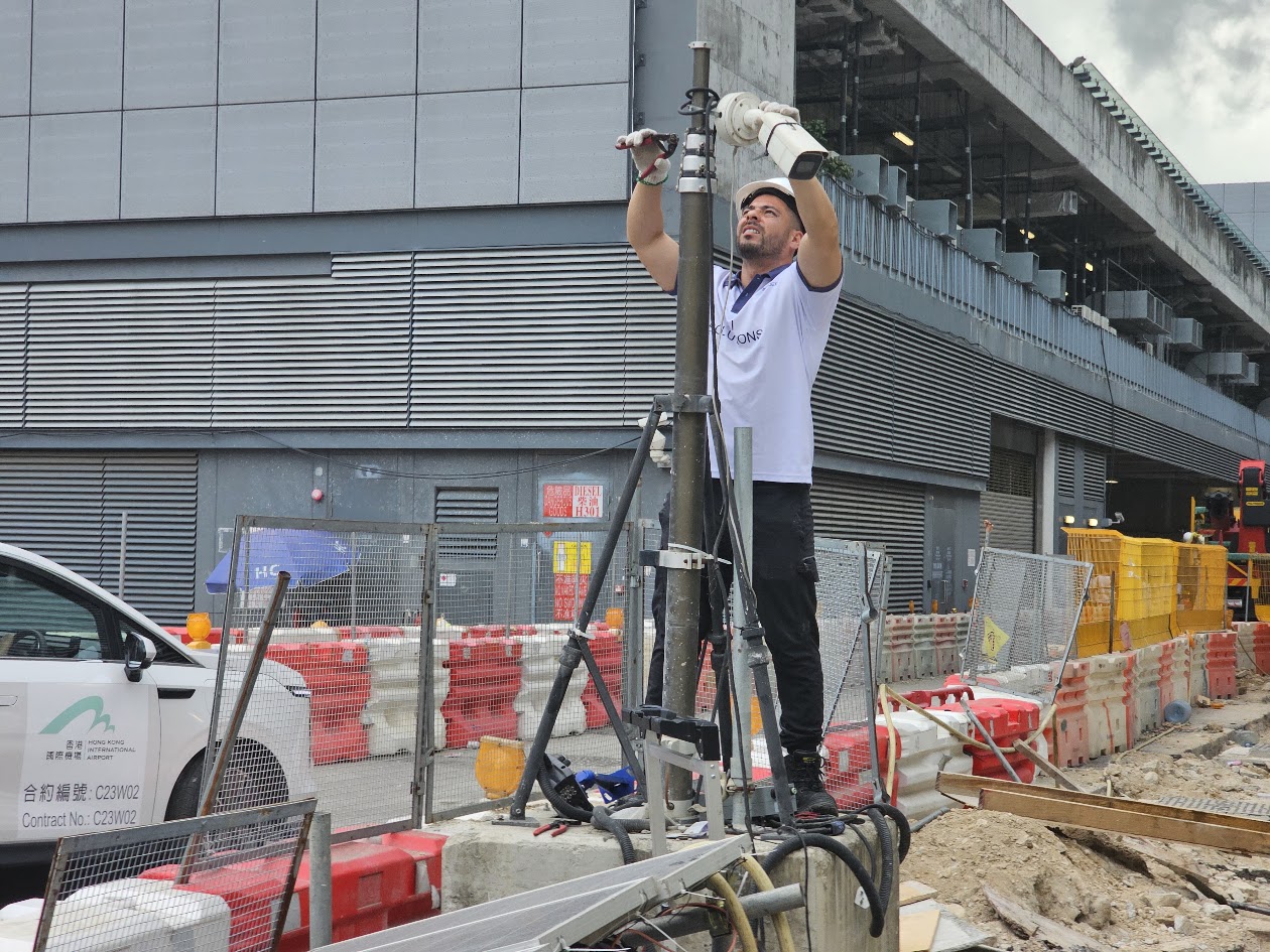 ImageDeep technician installing a camera stack on a tall telescopic pole at Hong Kong International Airport