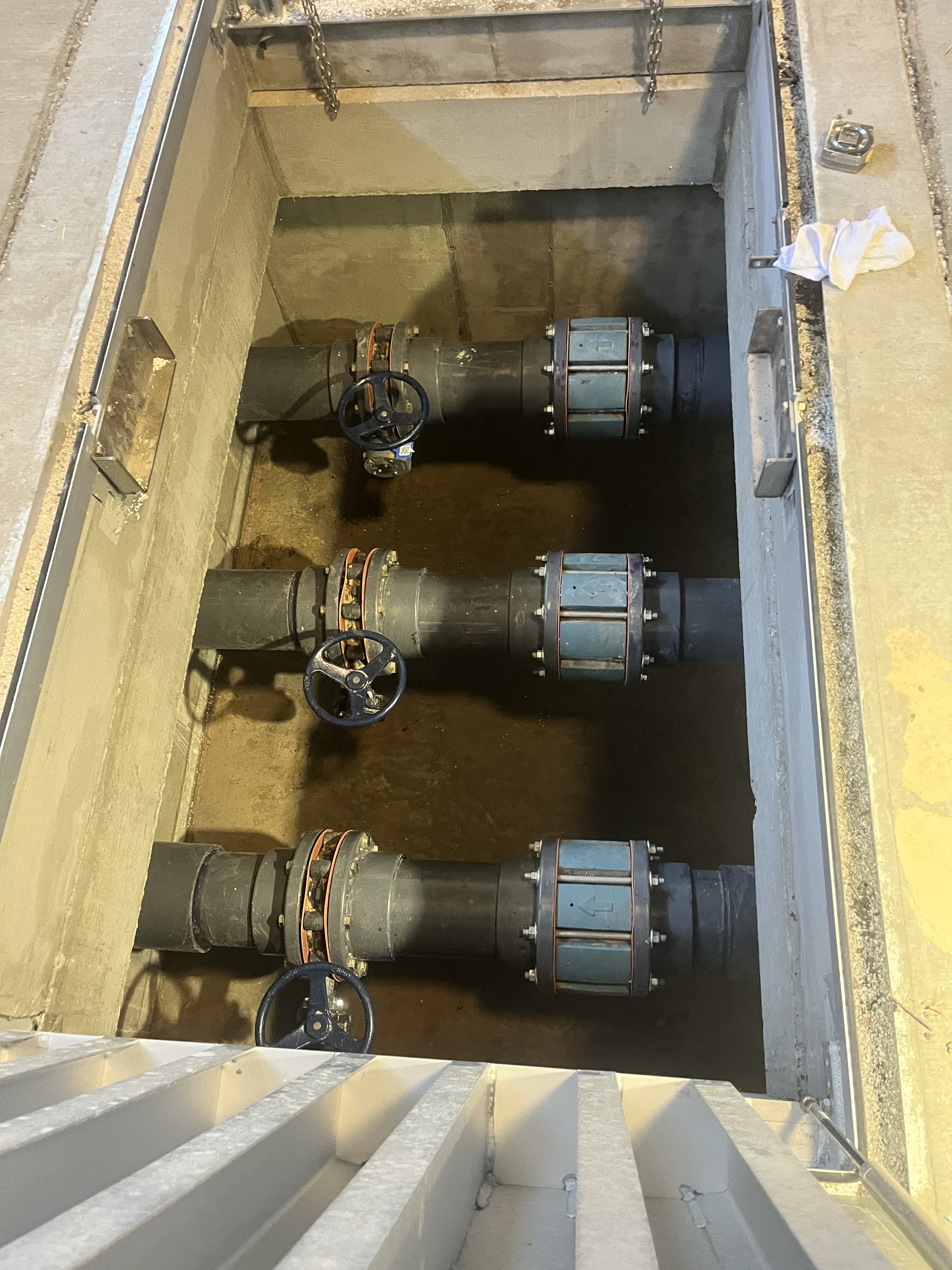 Pump station pipe manifold with valves and couplings in a concrete trench