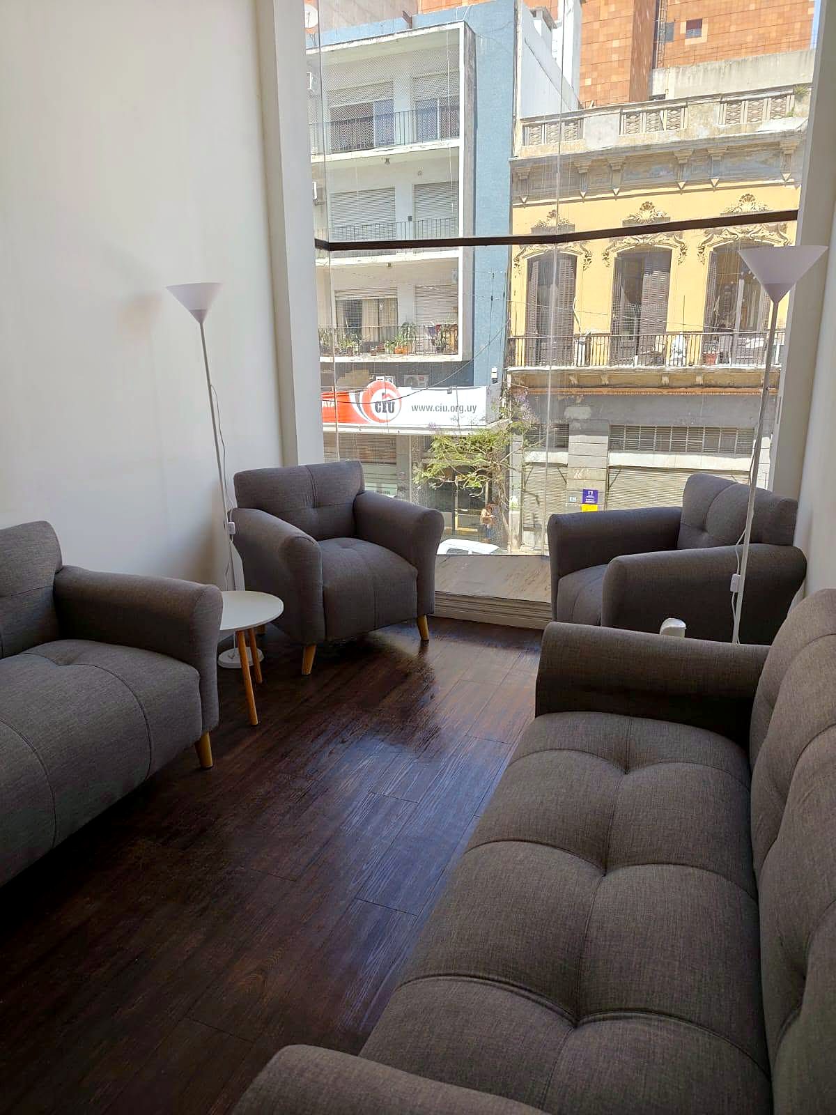 Living de Centro Smart 1 con sillones y gran ventanal hacia una fachada histórica de Montevideo